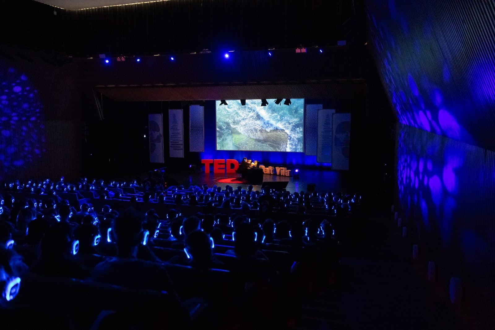 Un público de congreso al completo con auriculares AURA iluminados en un evento TEDx