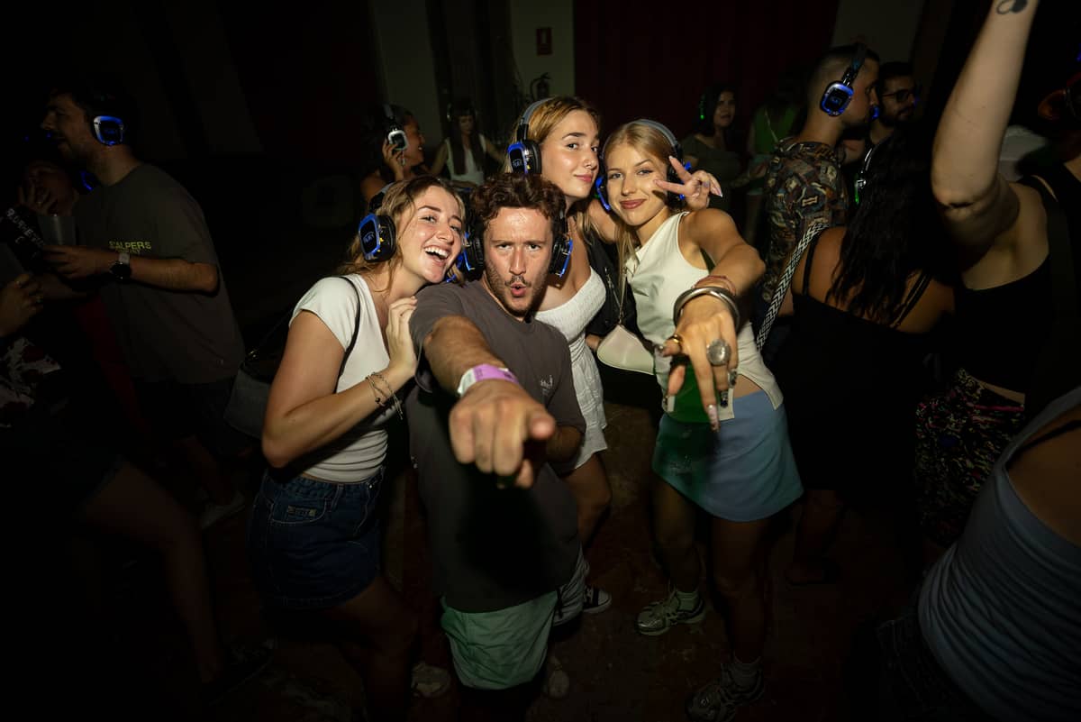 A crowd dancing in glowing AURA headphones at a silent disco party