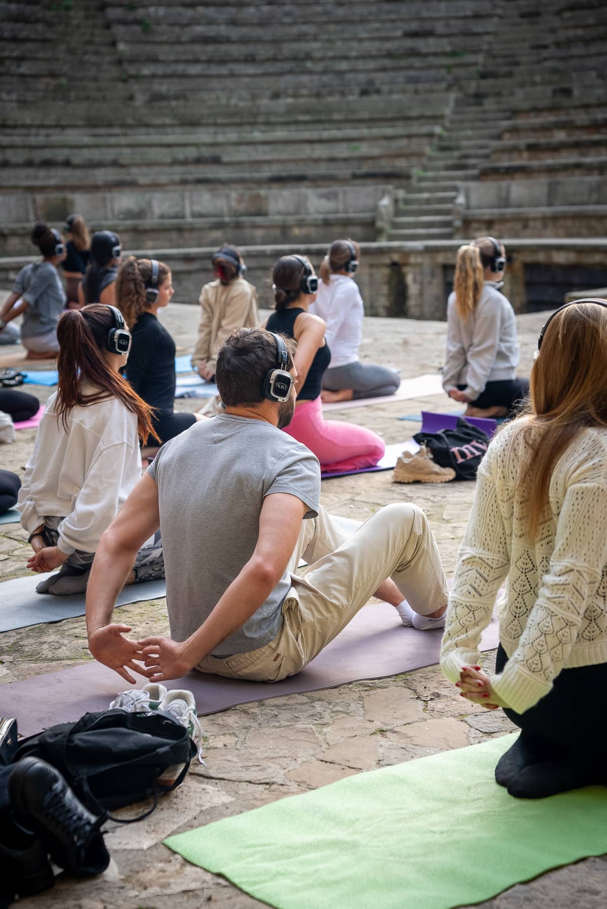People doing yoga in AURA headphones at an outdoor amphitheatre